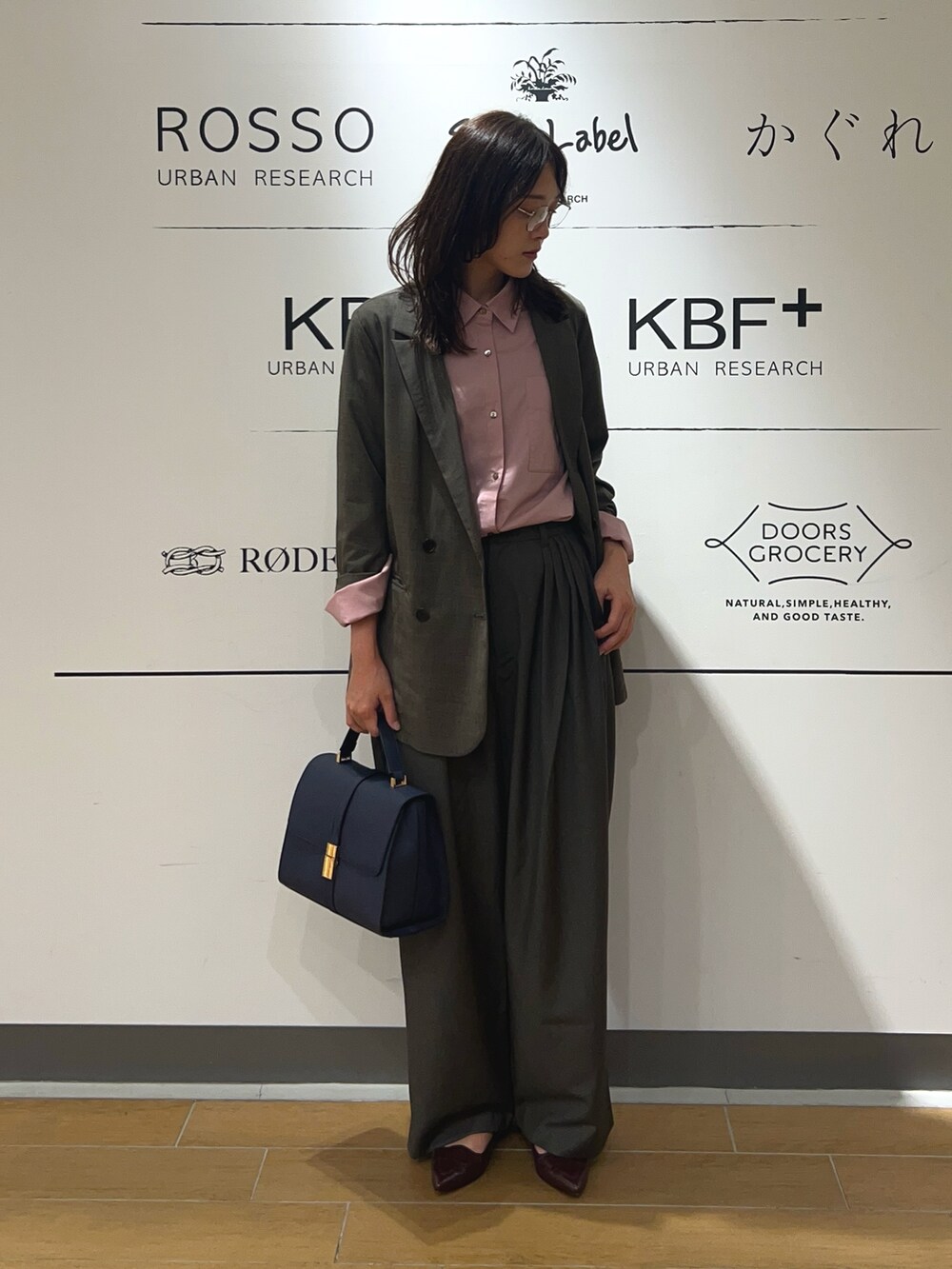 ピンク系のシャツ/ブラウス、ブラウン系のその他アウター、ブルー系のハンドバッグを着用したレディースの秋コーディネートの2枚目の写真