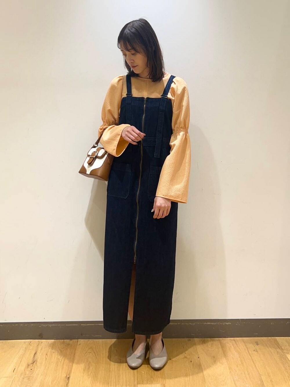 ブルー系のワンピース、グレー系のパンプス、オレンジ系のシャツ/ブラウスを着用したレディースの冬コーディネートの2枚目の写真