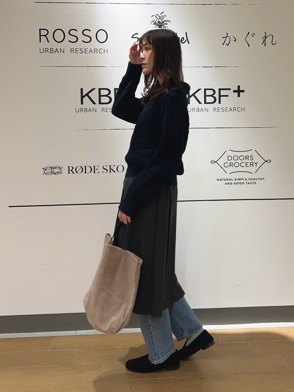 グレー系のスカート、ブルー系のニット/セーター、ベージュ系のトートバッグを着用したレディースの秋コーディネートの2枚目の写真