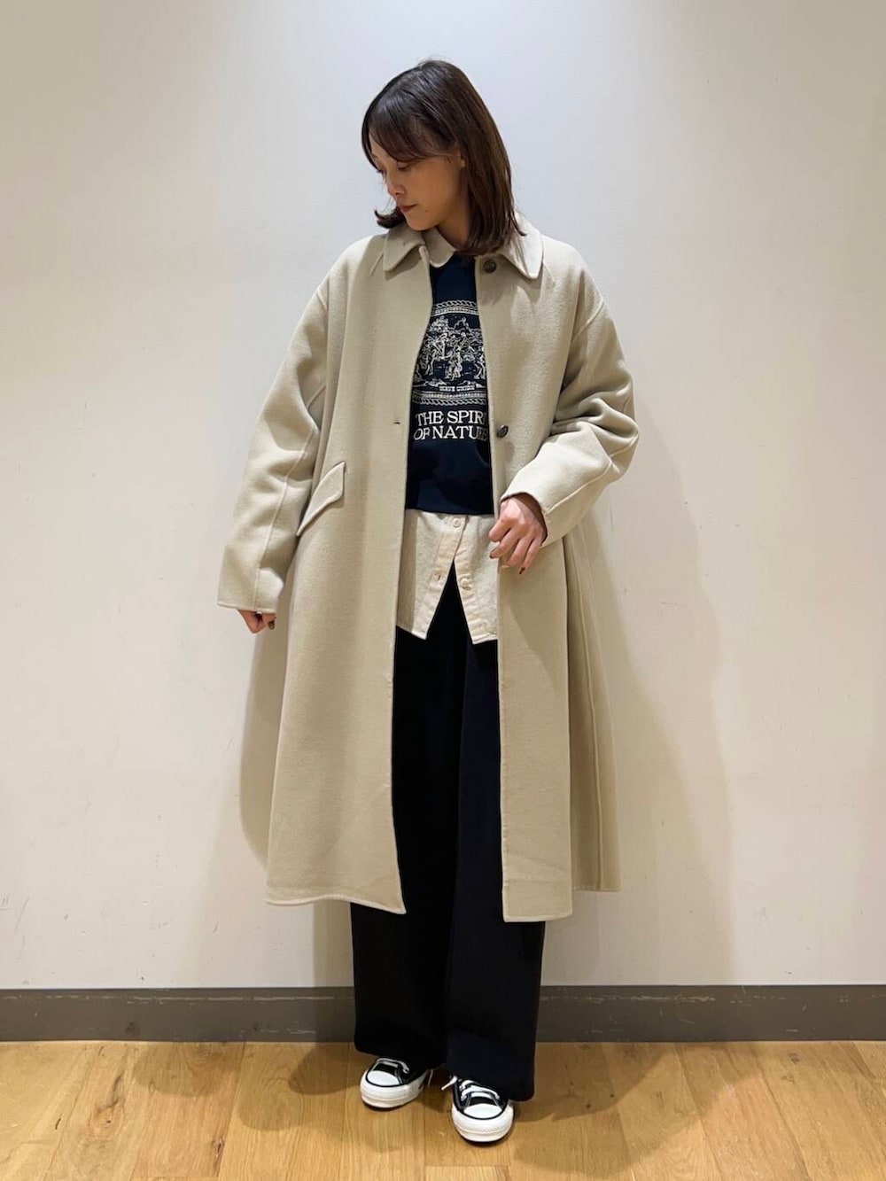 ブラック系のスニーカー、ベージュ系のステンカラーコート、ホワイト系のシャツ/ブラウスを着用したレディースの冬コーディネートの2枚目の写真