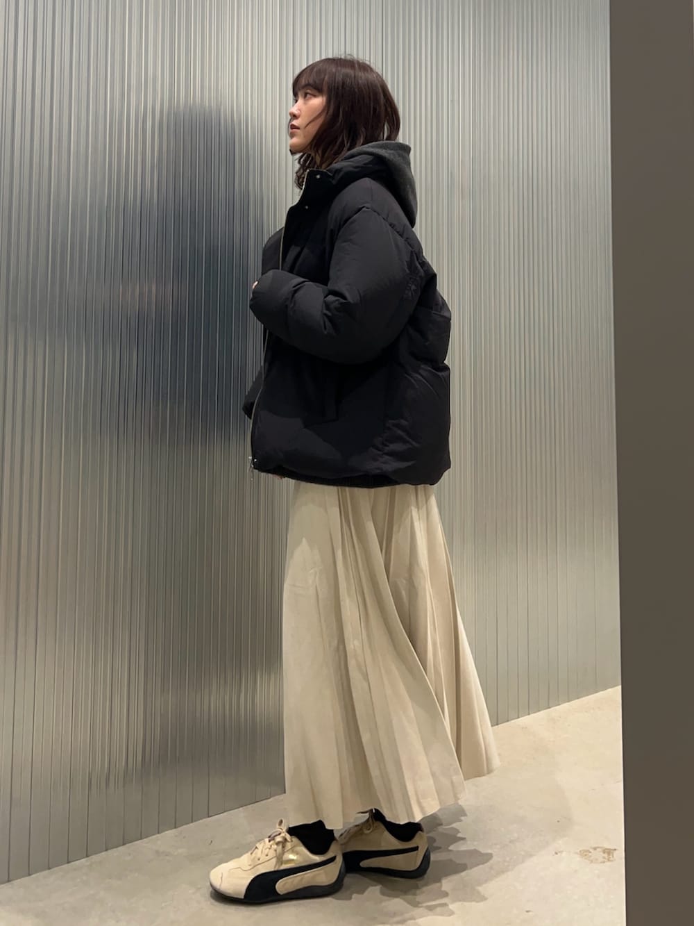 グレー系のニット/セーター、イエロー系のTシャツ/カットソー、ブラック系のダウンジャケット/コートを着用したレディースの冬コーディネートの2枚目の写真