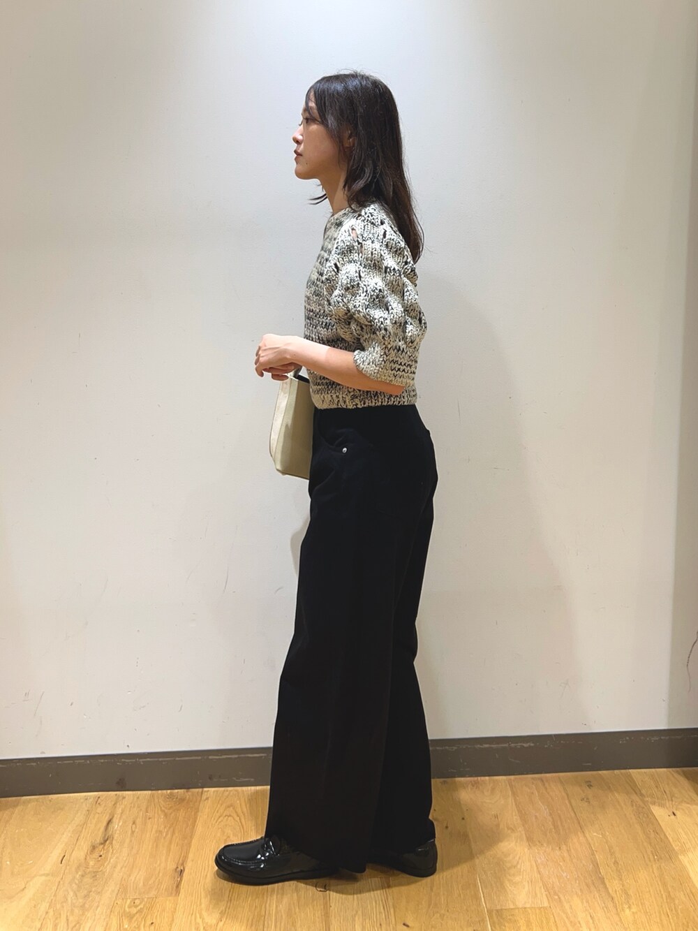 ホワイト系のニット/セーター、ブラック系のその他パンツ、ベージュ系のショルダーバッグを着用したレディースの秋コーディネートの2枚目の写真