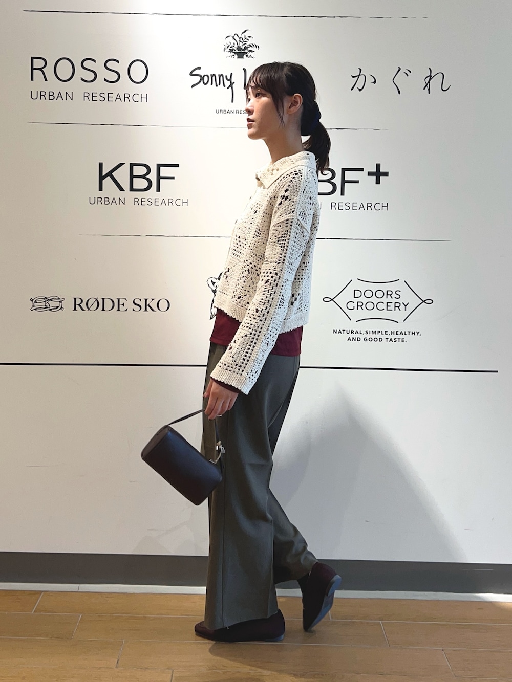 レッド系のTシャツ/カットソー、ベージュ系のカーディガン/ボレロ、ブラウン系のハンドバッグを着用したレディースの秋コーディネートの2枚目の写真