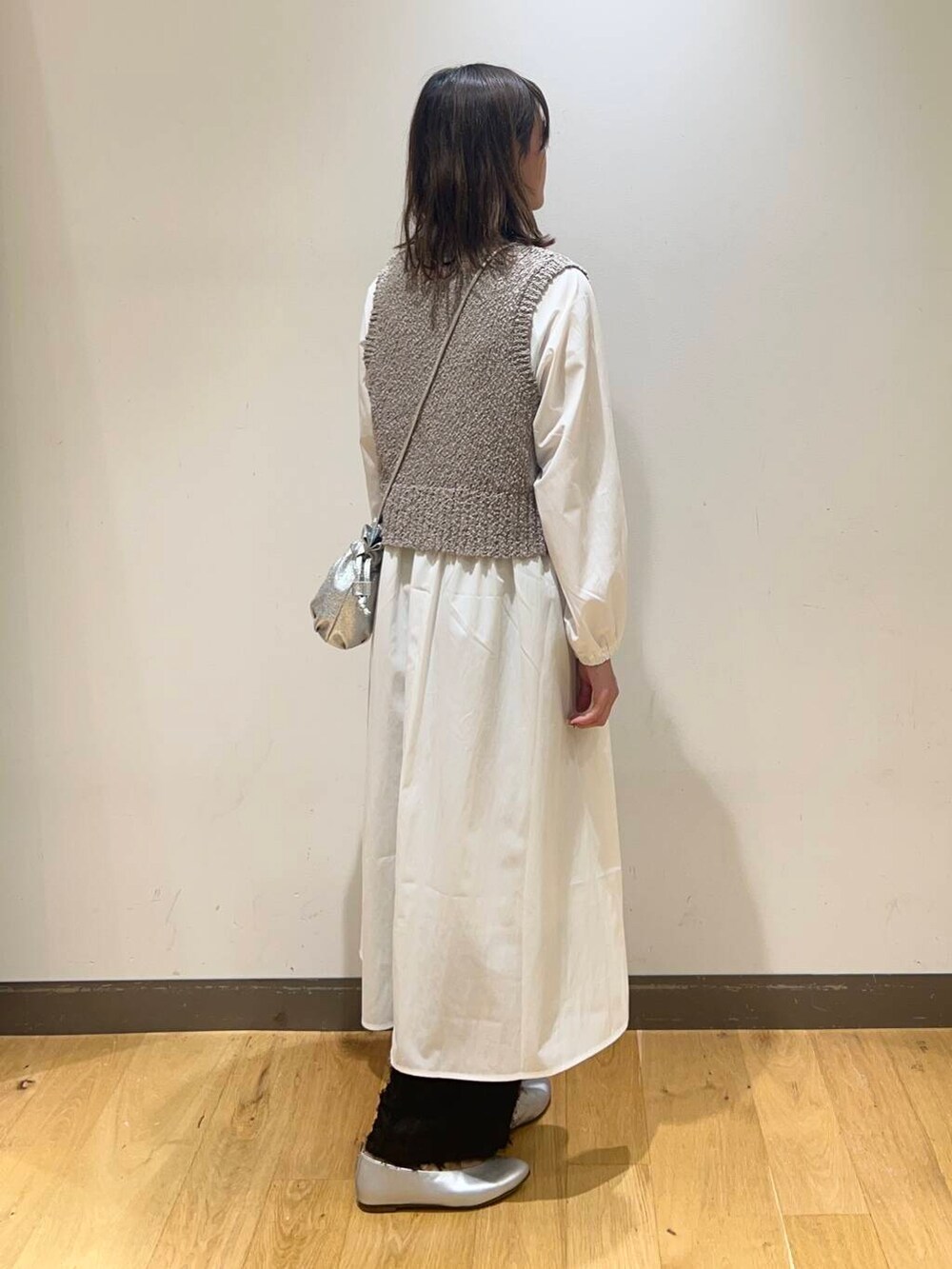 シルバー系のショルダーバッグ、シルバー系のパンプス、グレー系のワンピースを着用したレディースの冬コーディネートの4枚目の写真