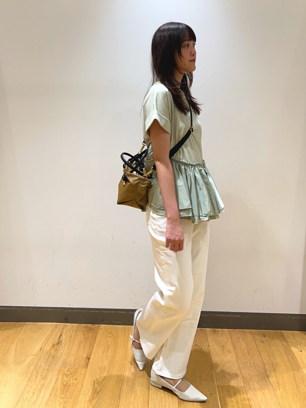 グリーン系のTシャツ/カットソー、ベージュ系のショルダーバッグ、ホワイト系のデニムパンツを着用したレディースの春コーディネートの3枚目の写真