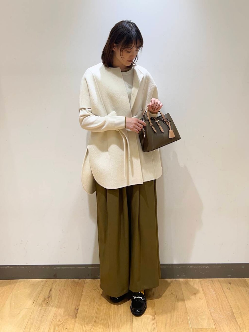 ブラック系のローファー、ブラウン系のハンドバッグ、ベージュ系のその他パンツを着用したレディースの冬コーディネートの2枚目の写真