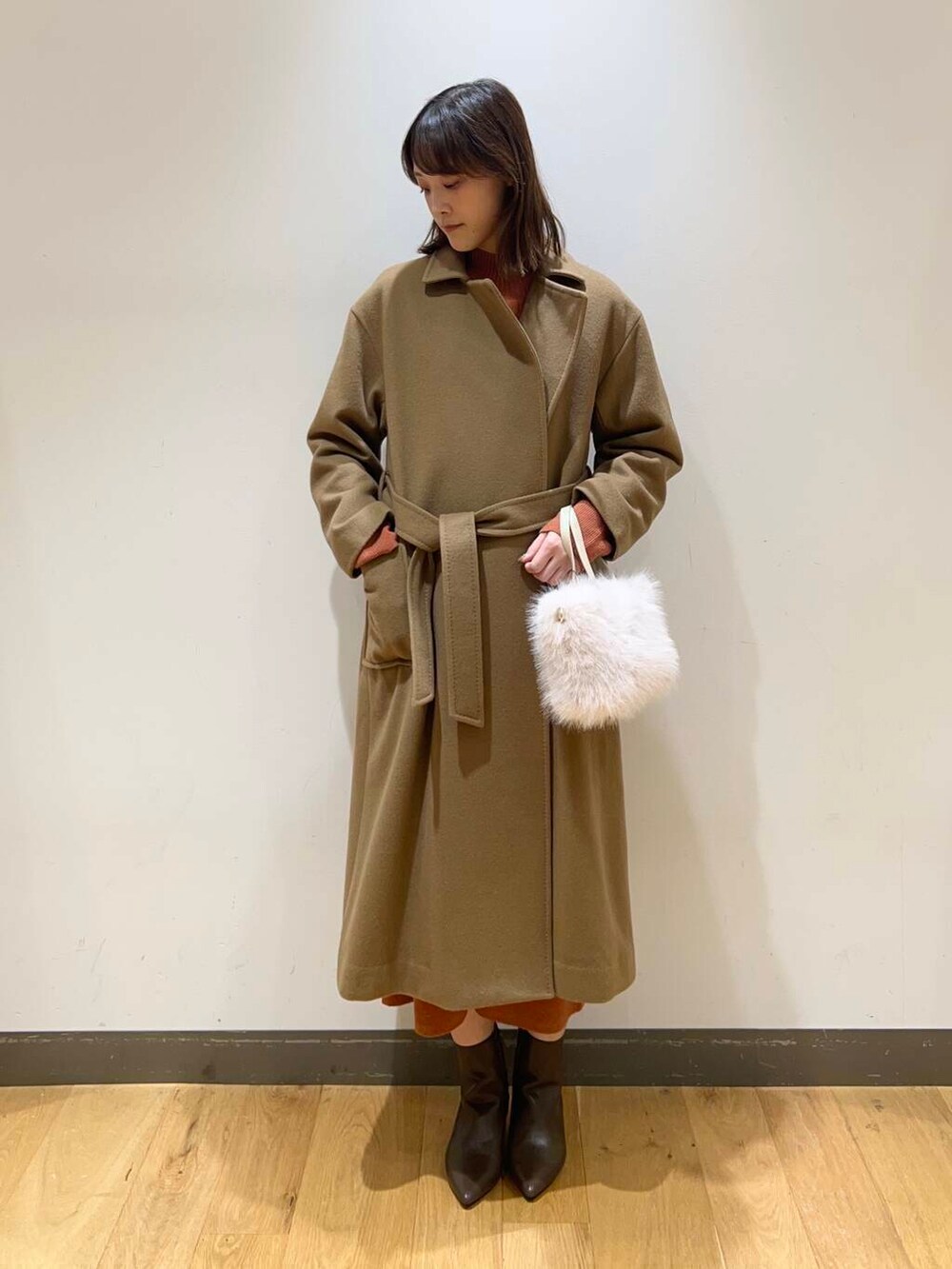 ブラウン系のブーツ、オレンジ系のワンピース、ベージュ系のその他アウターを着用したレディースの冬コーディネートの3枚目の写真