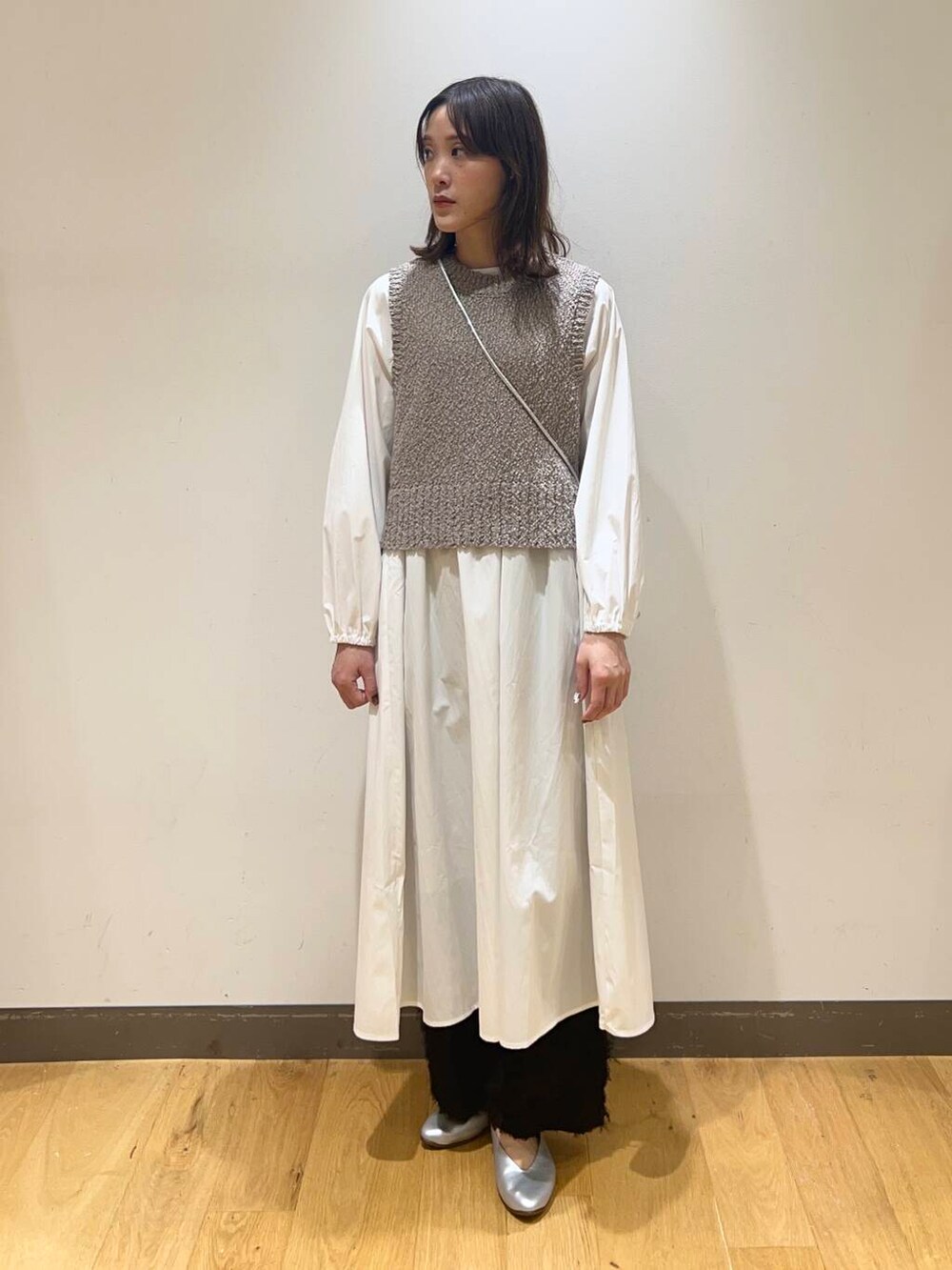 シルバー系のショルダーバッグ、シルバー系のパンプス、グレー系のワンピースを着用したレディースの冬コーディネートの2枚目の写真