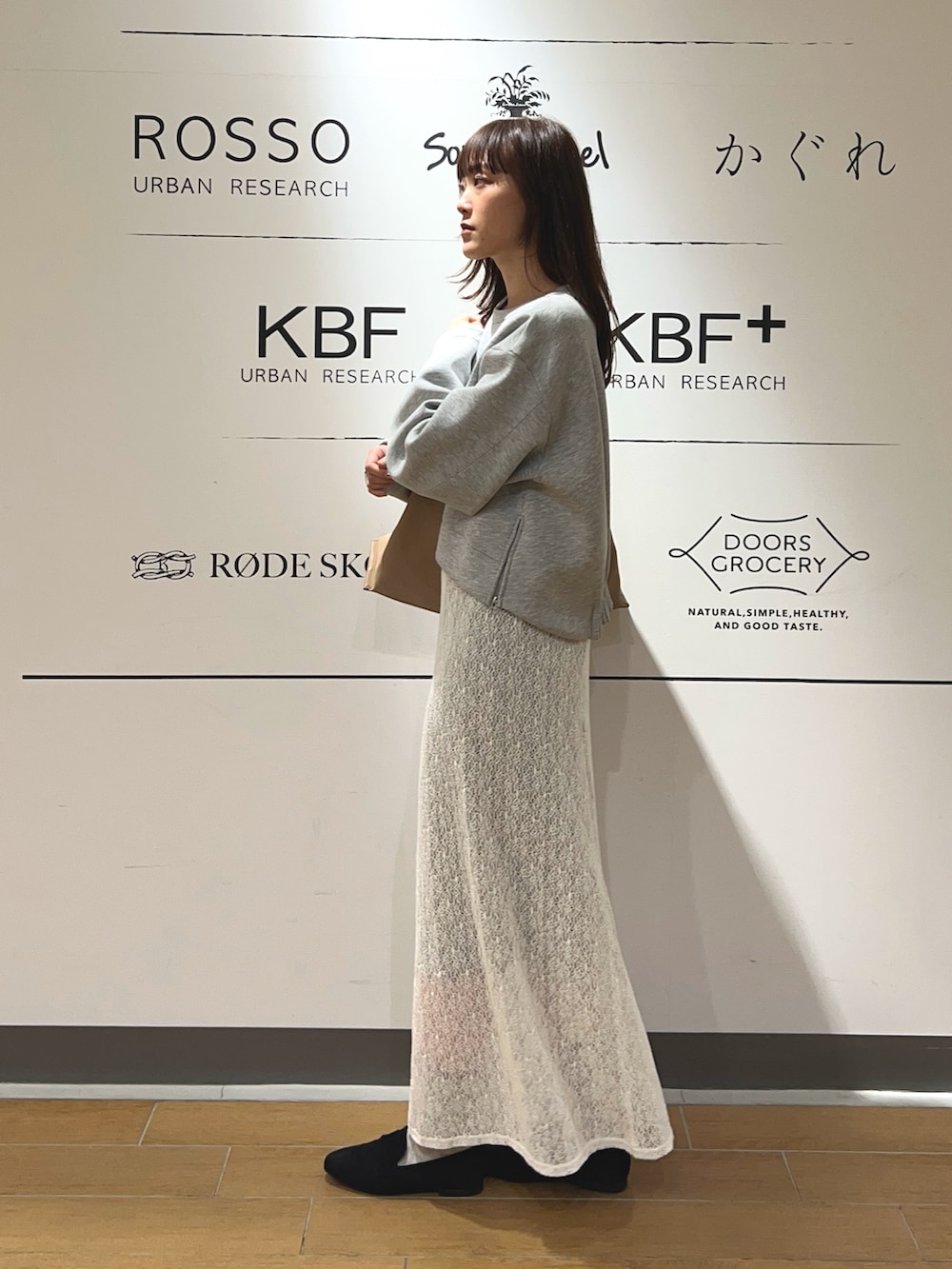 グレー系のスウェット、ホワイト系のスカート、ベージュ系のトートバッグを着用したレディースの冬コーディネートの3枚目の写真