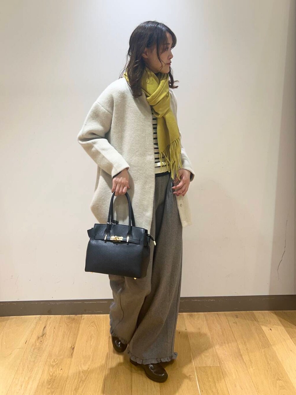 グレー系のその他パンツ、ホワイト系のニット/セーター、ブラック系のハンドバッグを着用したレディースの秋コーディネートの4枚目の写真