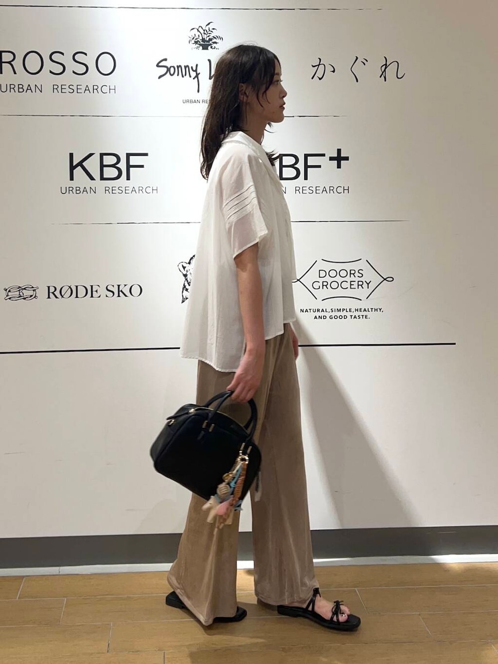 ホワイト系のタンクトップ、ブラック系のサンダル、ブラック系のボストンバッグを着用したレディースの夏コーディネートの2枚目の写真