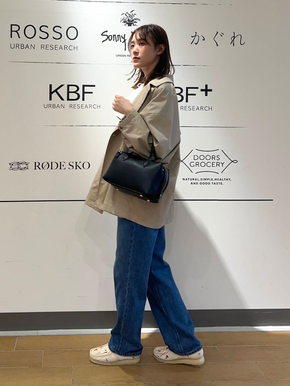 ベージュ系のトレンチコート、ブルー系のデニムパンツ、ブラック系のトートバッグを着用したレディースの春コーディネートの3枚目の写真