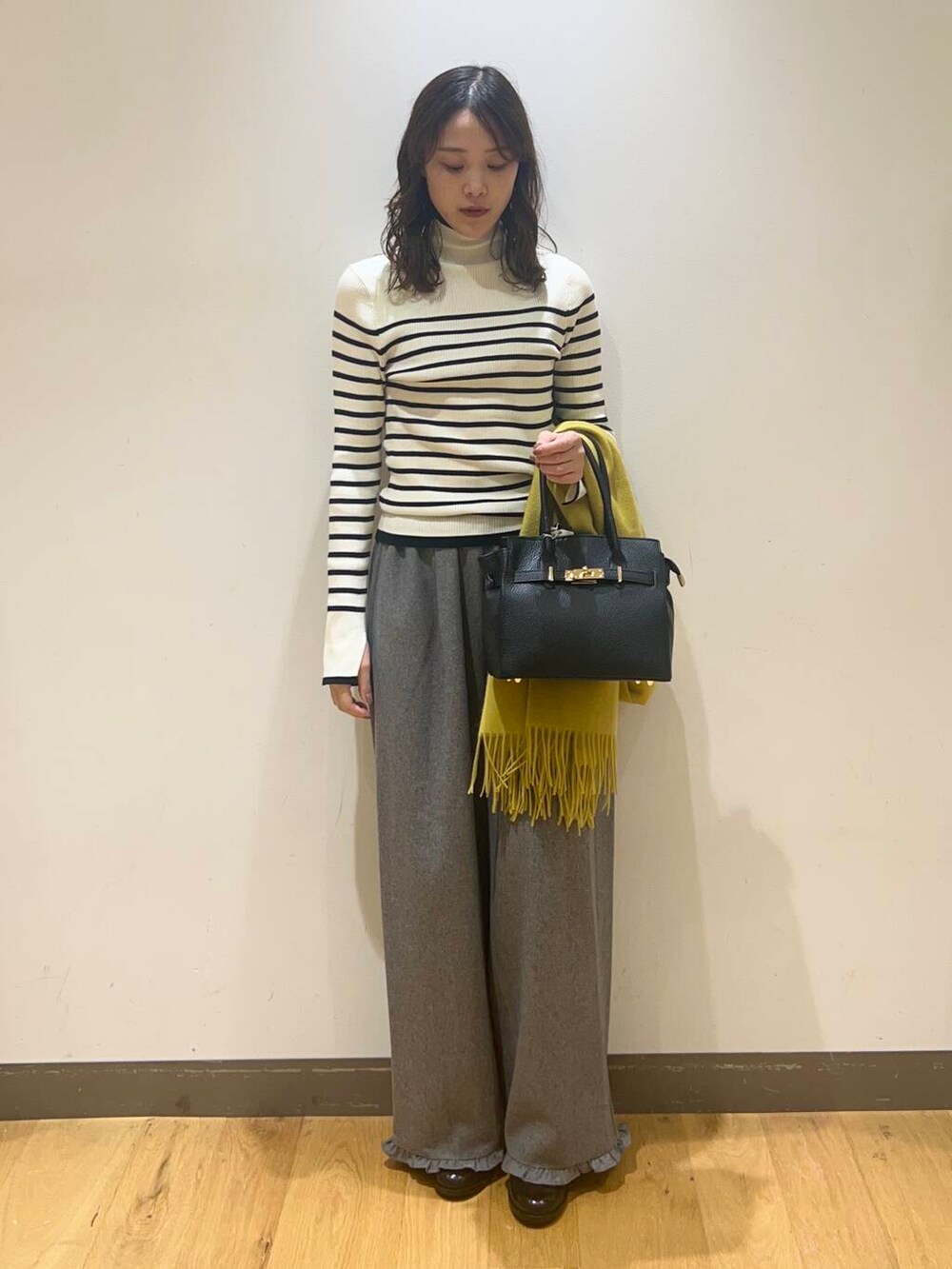 グレー系のその他パンツ、ホワイト系のニット/セーター、ブラック系のハンドバッグを着用したレディースの秋コーディネートの2枚目の写真