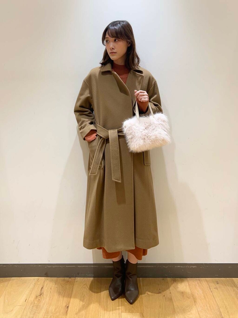 ブラウン系のブーツ、オレンジ系のワンピース、ベージュ系のその他アウターを着用したレディースの冬コーディネートの2枚目の写真