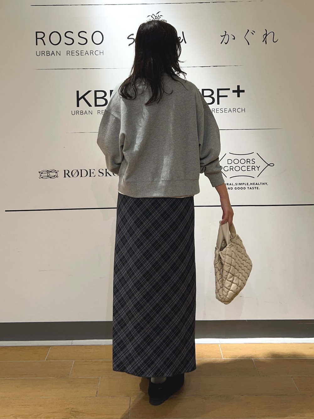 ホワイト系のハンドバッグ、ブルー系のスカート、ブラック系のブーツを着用したレディースの秋コーディネートの4枚目の写真