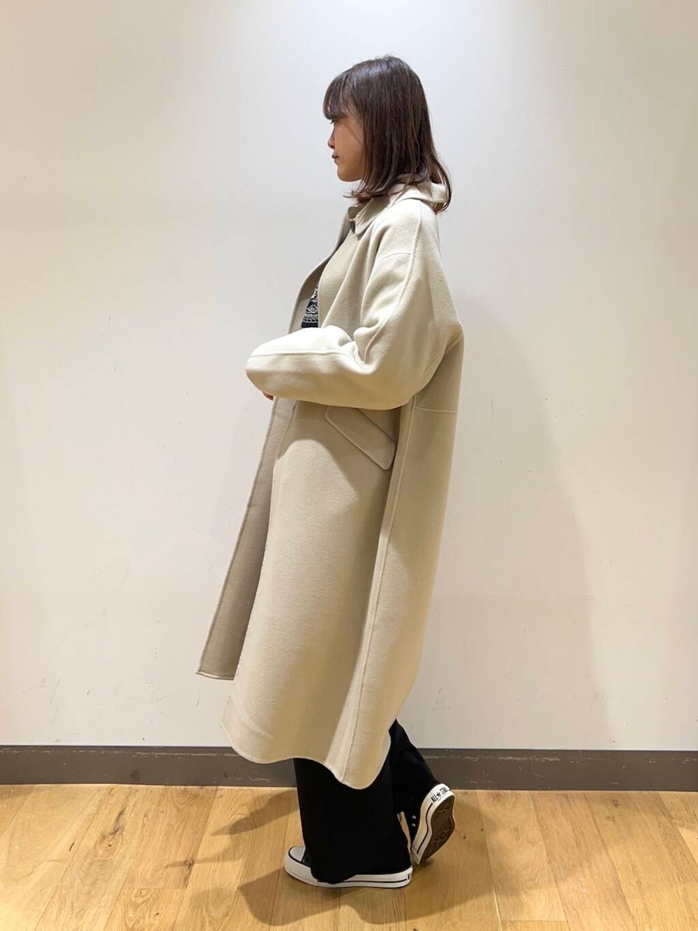 ブラック系のスニーカー、ベージュ系のステンカラーコート、ホワイト系のシャツ/ブラウスを着用したレディースの冬コーディネートの3枚目の写真