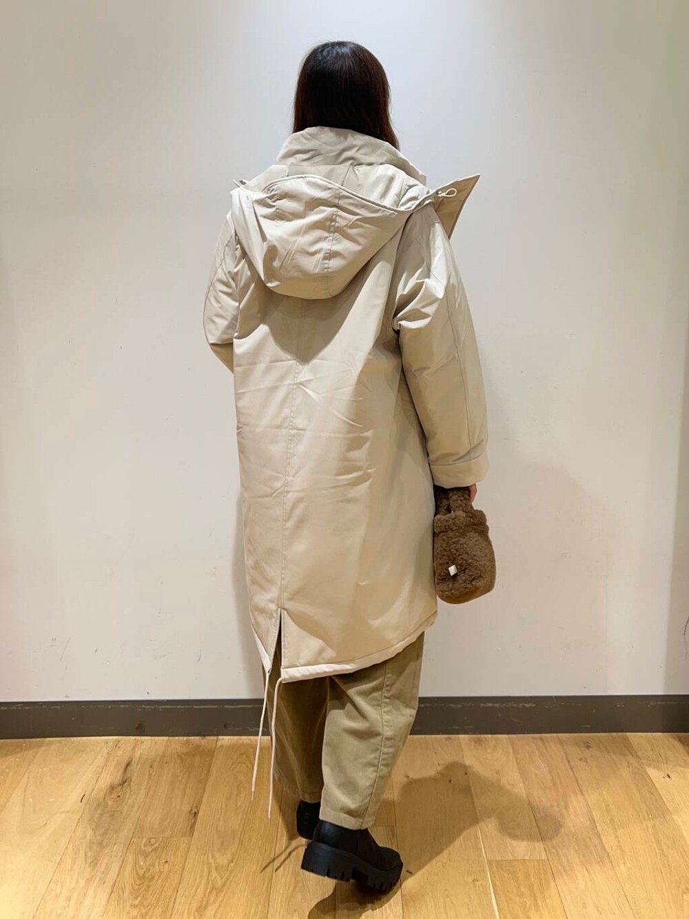 ブラック系のブーツ、ブラウン系のハンドバッグ、ベージュ系のダウンジャケット/コートを着用したレディースの冬コーディネートの3枚目の写真