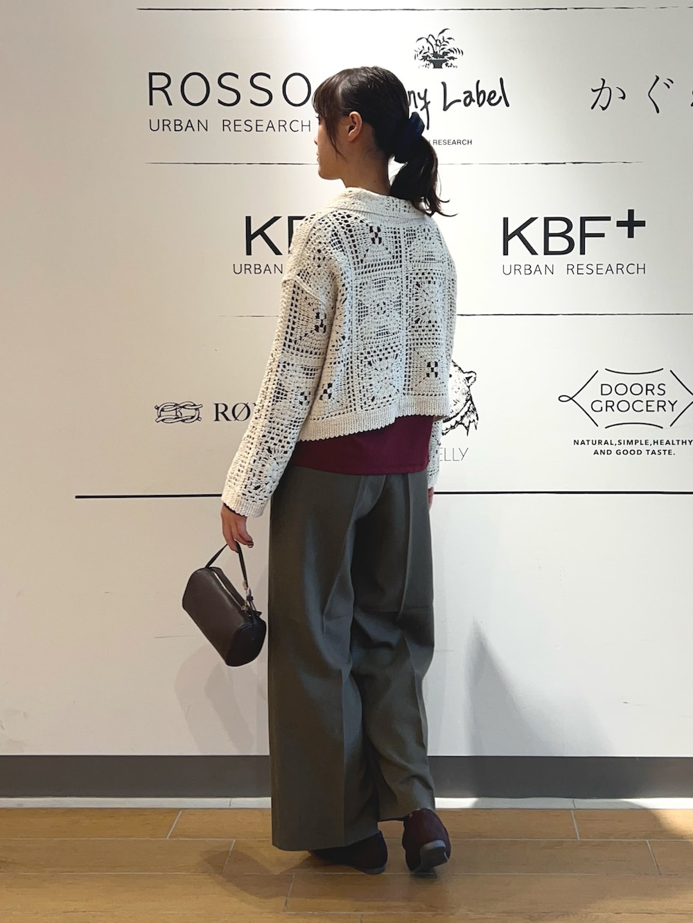 レッド系のTシャツ/カットソー、ベージュ系のカーディガン/ボレロ、ブラウン系のハンドバッグを着用したレディースの秋コーディネートの3枚目の写真