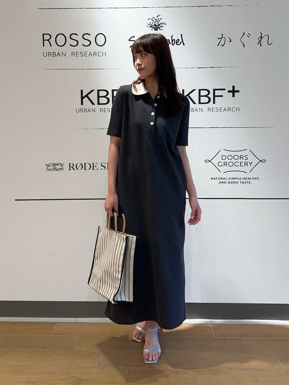 グレー系のワンピース、ブラック系のトートバッグ、シルバー系のサンダルを着用したレディースの春コーディネートの2枚目の写真
