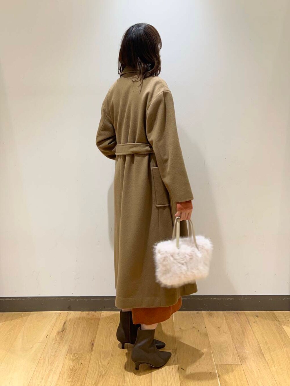 ブラウン系のブーツ、オレンジ系のワンピース、ベージュ系のその他アウターを着用したレディースの冬コーディネートの4枚目の写真