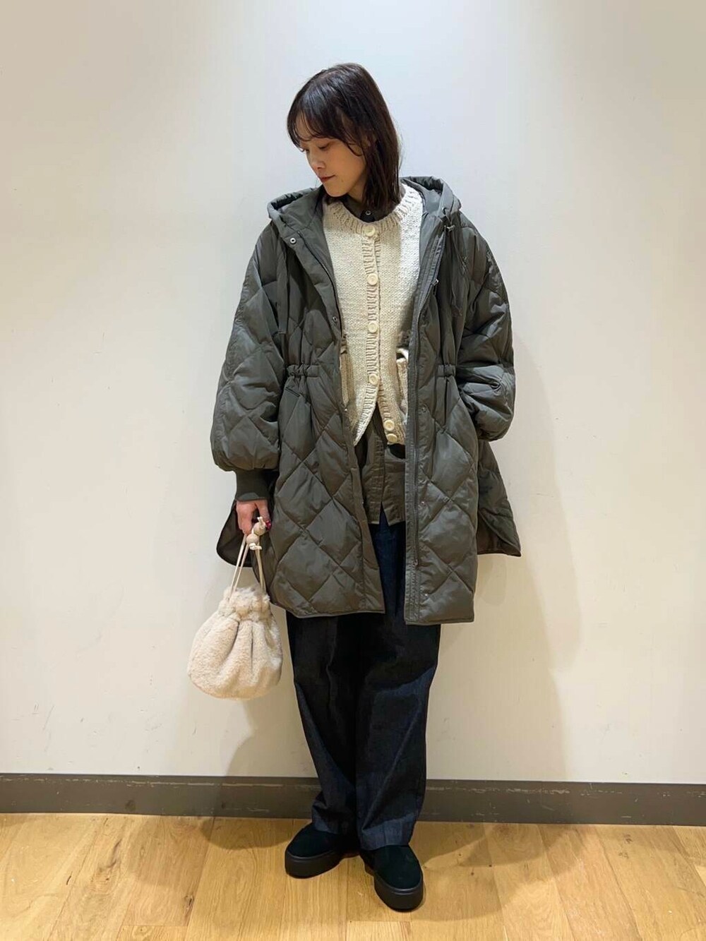 ブルー系のデニムパンツ、ブラック系のブーツ、ホワイト系のショルダーバッグを着用したレディースの冬コーディネートの2枚目の写真