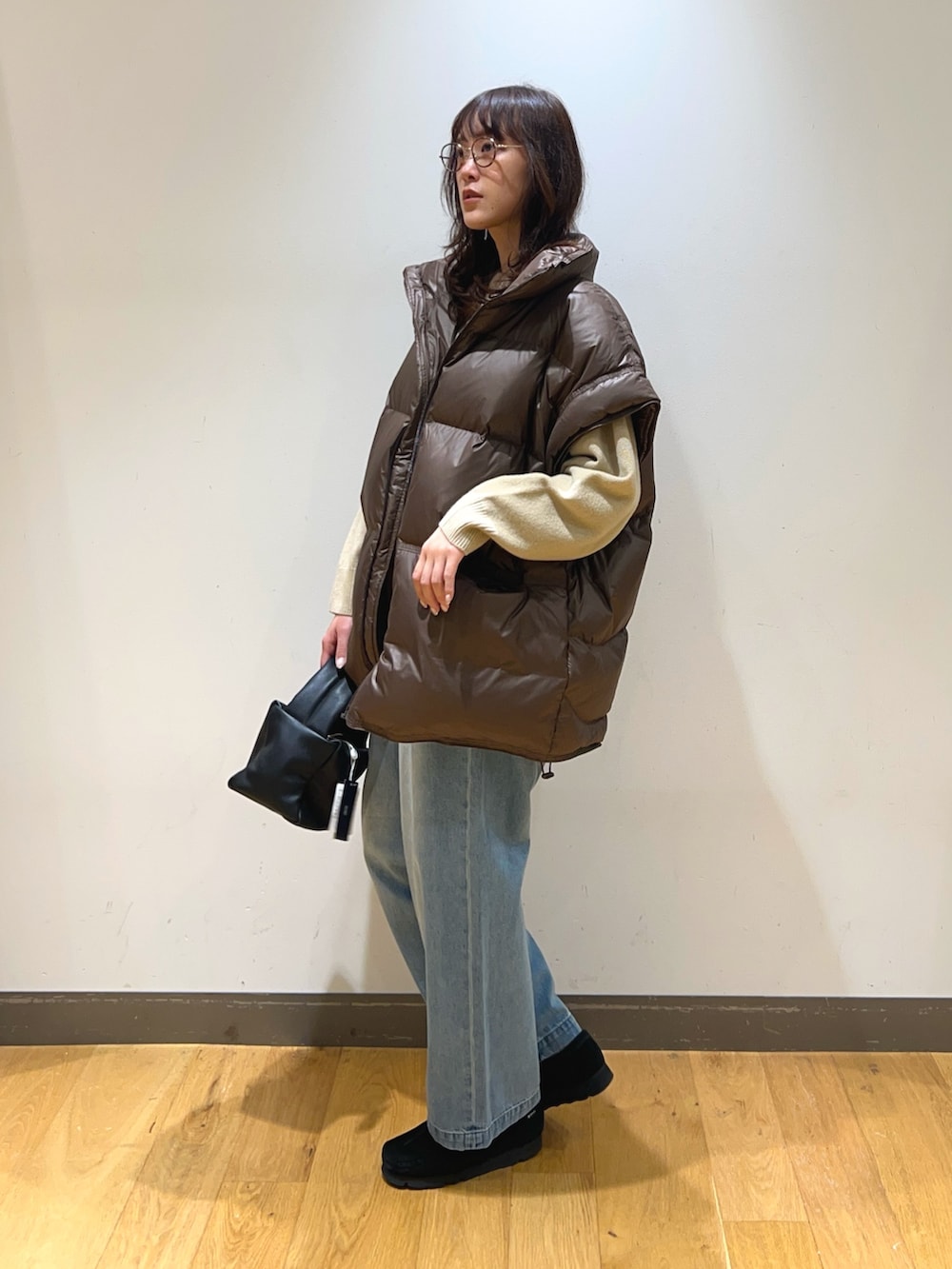 ブラック系のブーツ、ブラウン系のダウンベスト、ブラック系のハンドバッグを着用したレディースの冬コーディネートの2枚目の写真