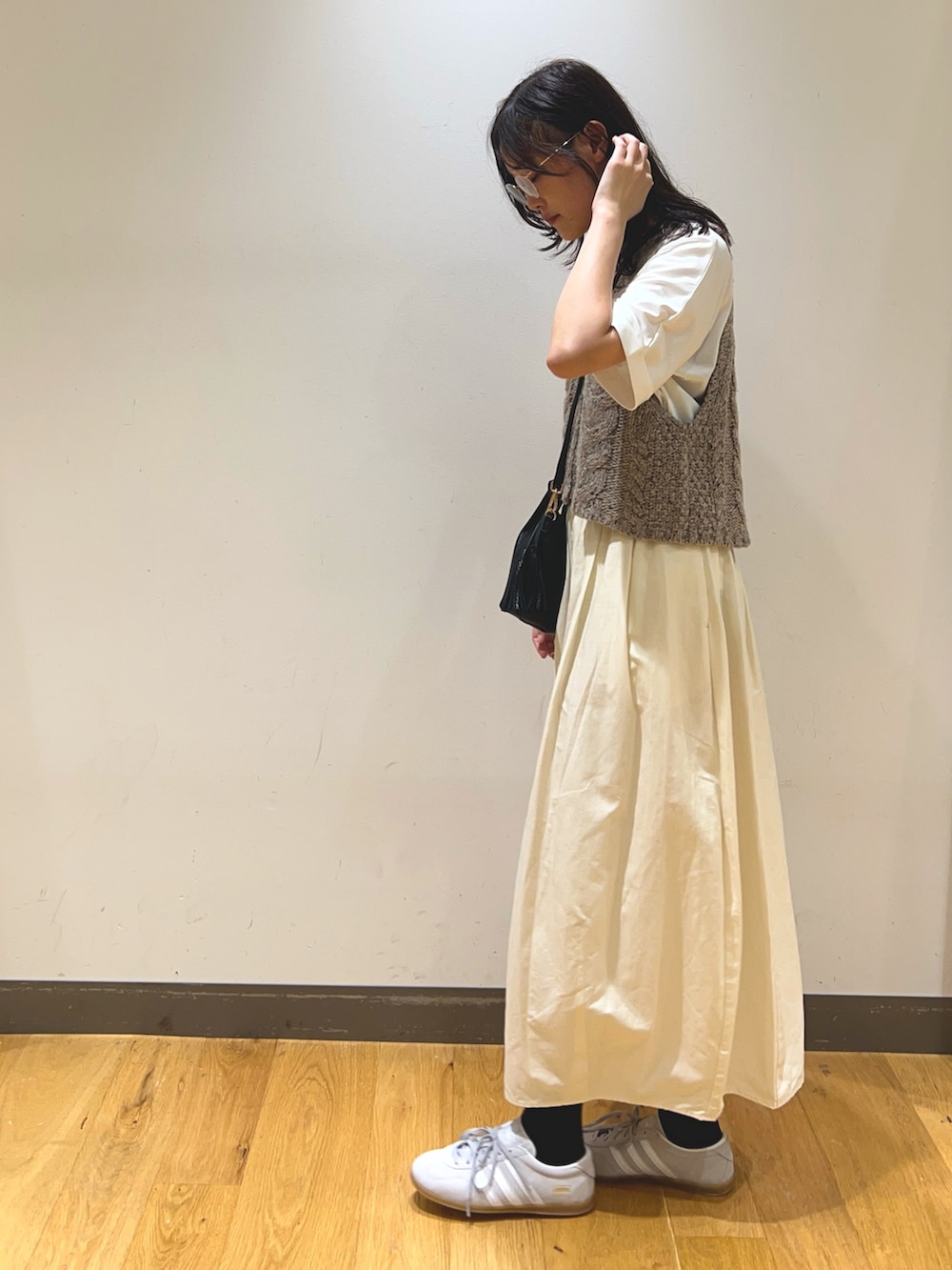 ホワイト系のスカート、ホワイト系のTシャツ/カットソー、ベージュ系のニット/セーターを着用したレディースの秋コーディネートの2枚目の写真