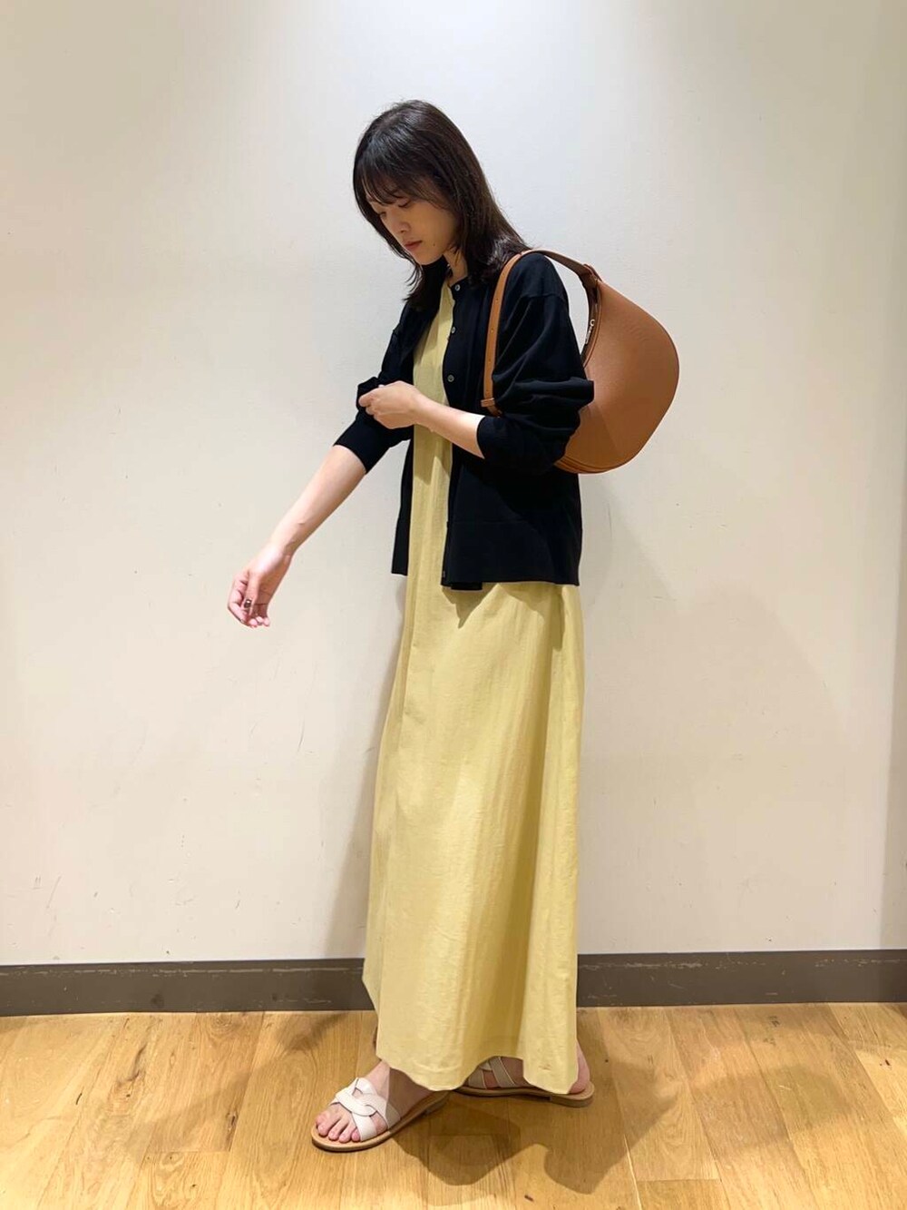 ホワイト系のサンダル、イエロー系のワンピース、ブラウン系のハンドバッグを着用したレディースの夏コーディネートの2枚目の写真