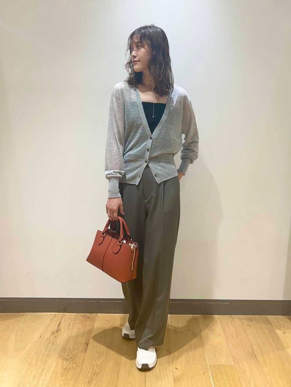 ブラック系のキャミソール、オレンジ系のハンドバッグ、グレー系のカーディガン/ボレロを着用したレディースの秋コーディネートの2枚目の写真