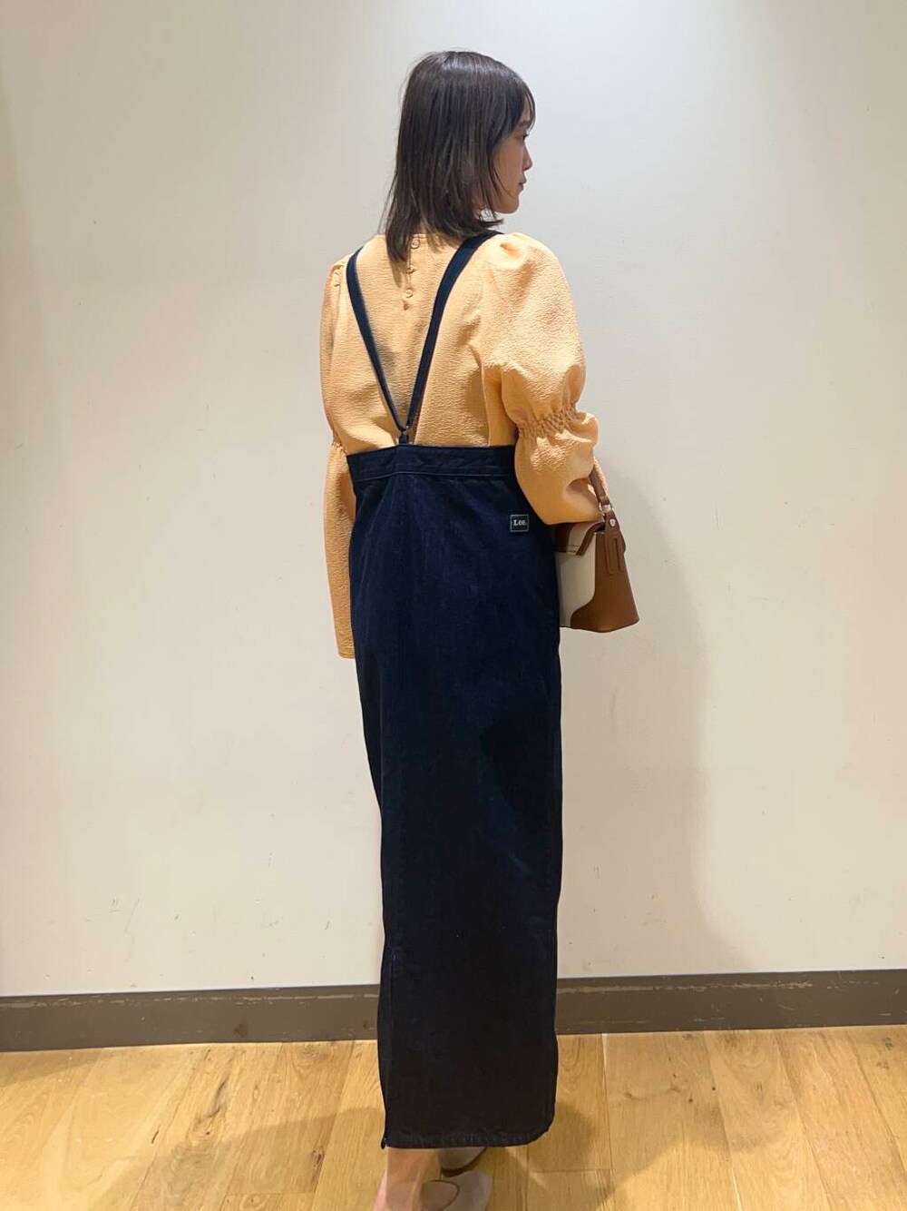 ブルー系のワンピース、グレー系のパンプス、オレンジ系のシャツ/ブラウスを着用したレディースの冬コーディネートの4枚目の写真