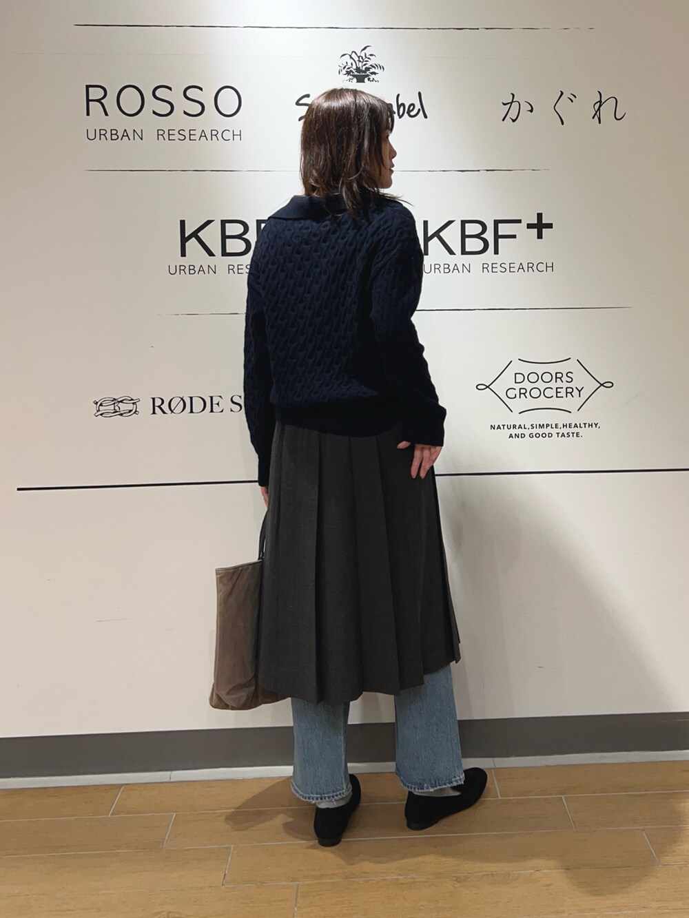 グレー系のスカート、ブルー系のニット/セーター、ベージュ系のトートバッグを着用したレディースの秋コーディネートの3枚目の写真