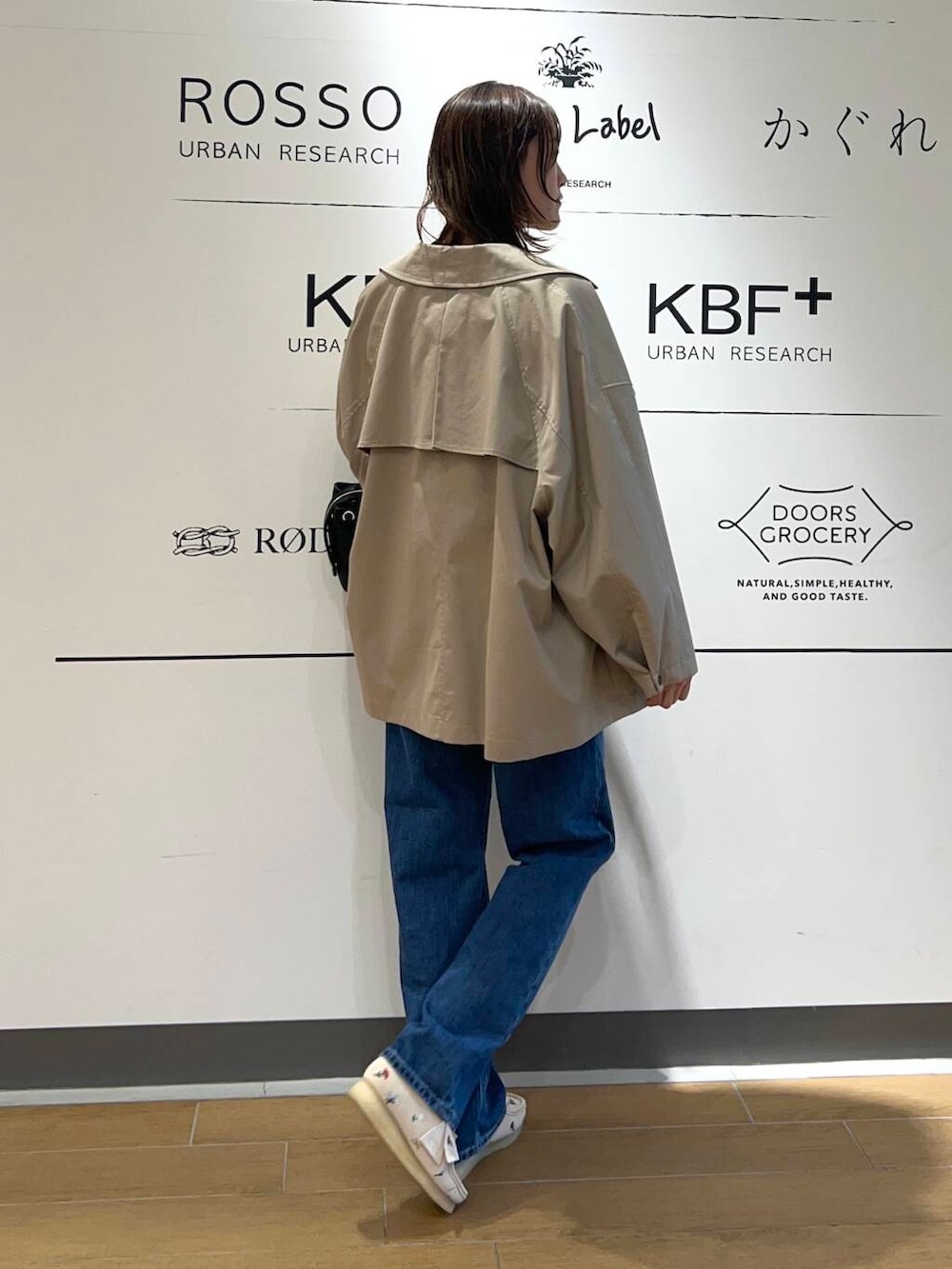 ベージュ系のトレンチコート、ブルー系のデニムパンツ、ブラック系のトートバッグを着用したレディースの春コーディネートの4枚目の写真