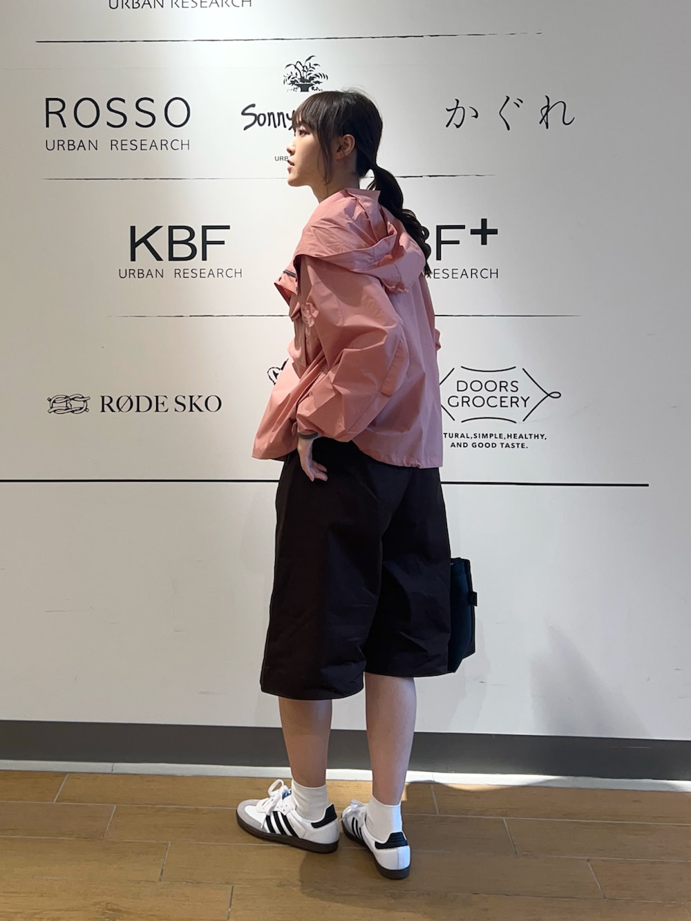 ピンク系のナイロンジャケット、ベージュ系のタンクトップ、ブラック系のショルダーバッグを着用したレディースの春コーディネートの2枚目の写真