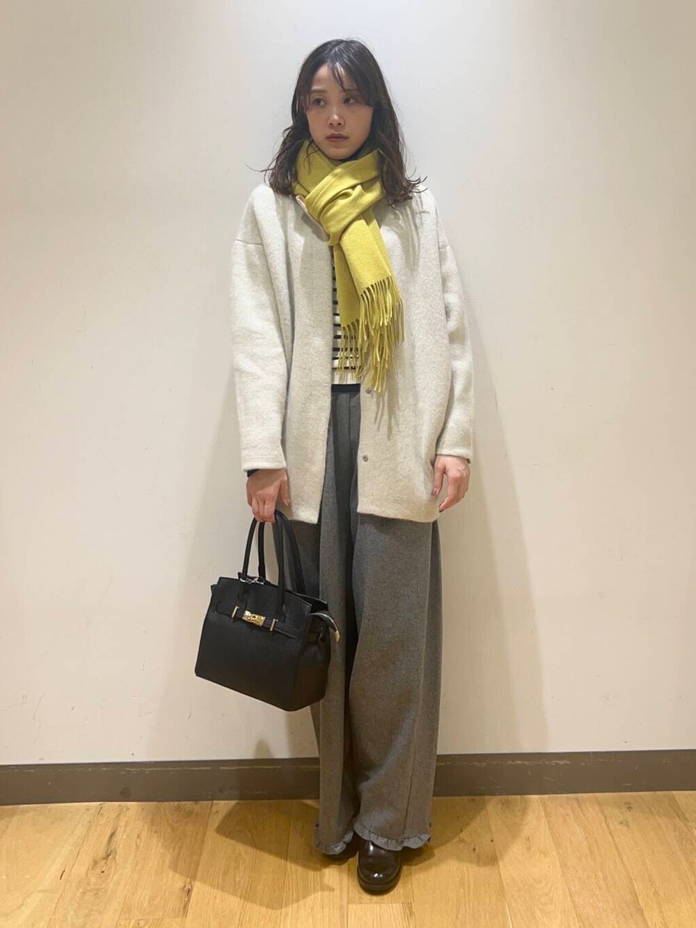 グレー系のその他パンツ、ホワイト系のニット/セーター、ブラック系のハンドバッグを着用したレディースの秋コーディネートの3枚目の写真