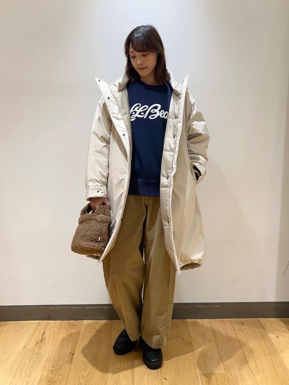 ブラック系のブーツ、ブラウン系のハンドバッグ、ベージュ系のダウンジャケット/コートを着用したレディースの冬コーディネートの2枚目の写真