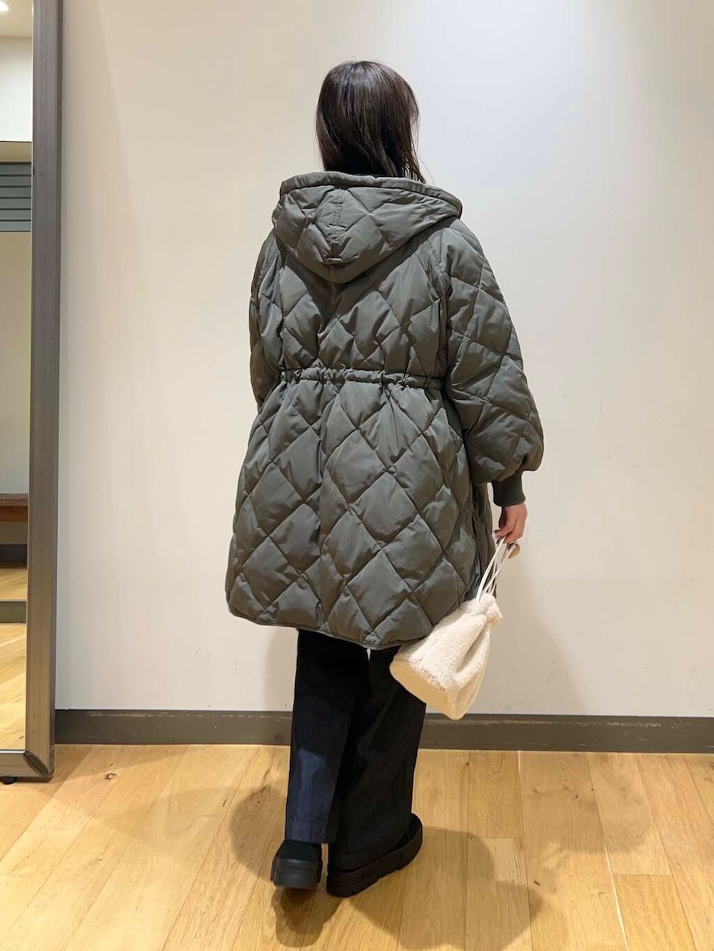 ブルー系のデニムパンツ、ブラック系のブーツ、ホワイト系のショルダーバッグを着用したレディースの冬コーディネートの4枚目の写真