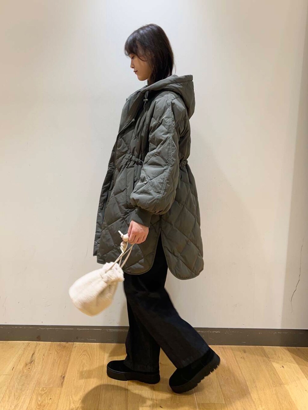 ブルー系のデニムパンツ、ブラック系のブーツ、ホワイト系のショルダーバッグを着用したレディースの冬コーディネートの3枚目の写真