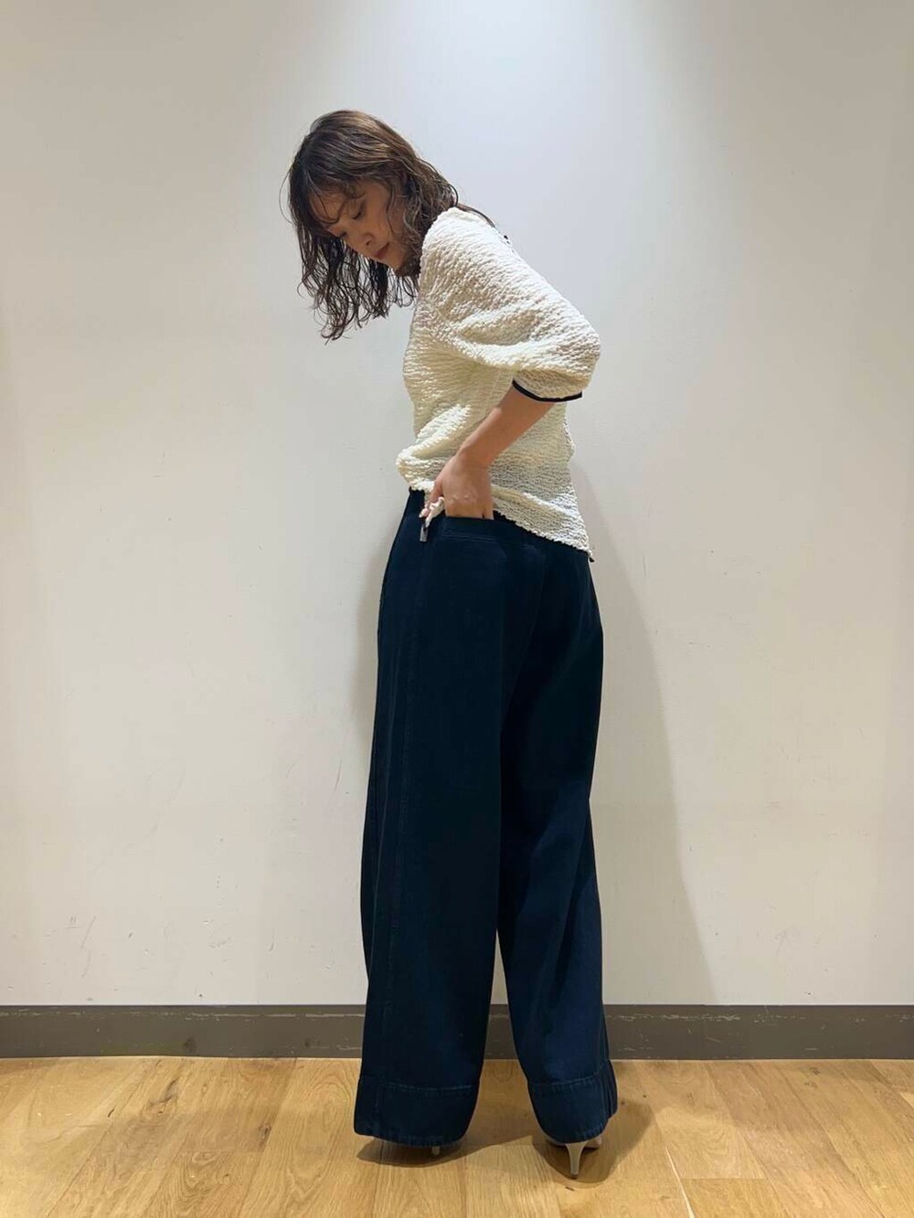 ブラウン系のパンプス、ブラック系のデニムパンツ、ホワイト系のキャミソールを着用したレディースの秋コーディネートの4枚目の写真