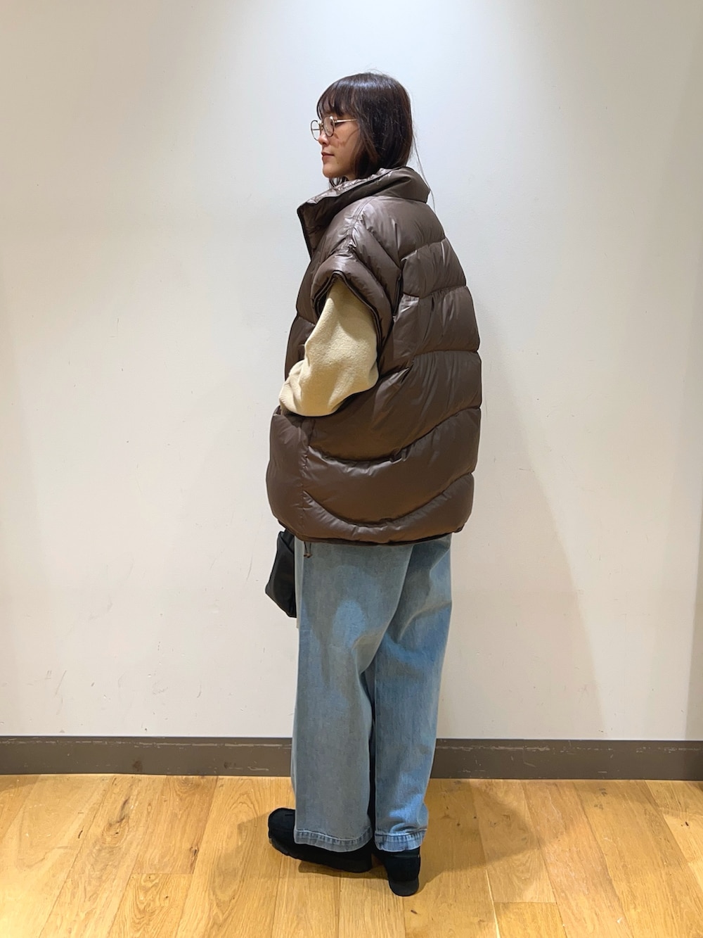 ブラック系のブーツ、ブラウン系のダウンベスト、ブラック系のハンドバッグを着用したレディースの冬コーディネートの5枚目の写真