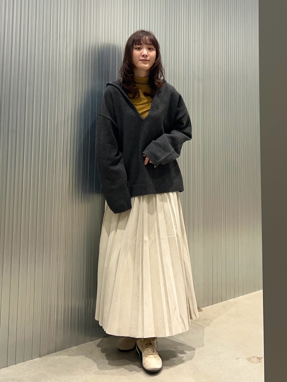 グレー系のニット/セーター、イエロー系のTシャツ/カットソー、ブラック系のダウンジャケット/コートを着用したレディースの冬コーディネートの3枚目の写真