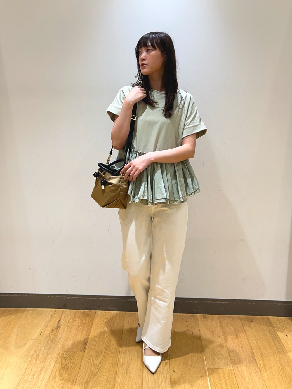 グリーン系のTシャツ/カットソー、ベージュ系のショルダーバッグ、ホワイト系のデニムパンツを着用したレディースの春コーディネートの2枚目の写真
