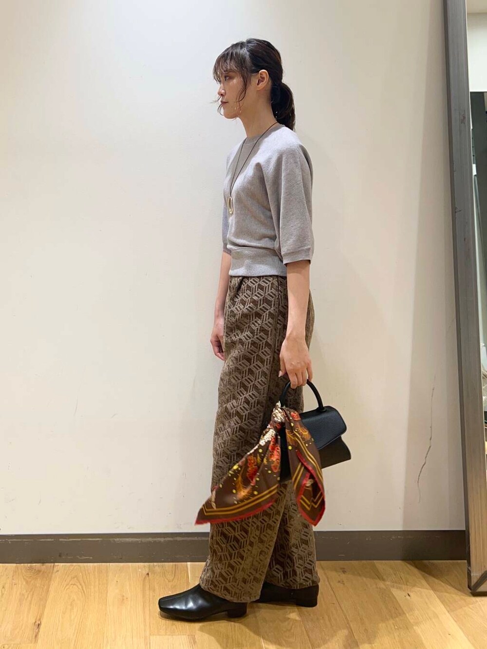 ブラック系のショルダーバッグ、ブラウン系のその他パンツ、グレー系のニット/セーターを着用したレディースの秋コーディネートの2枚目の写真