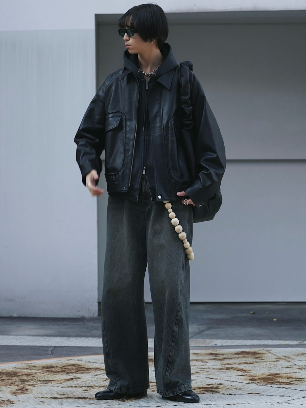 ブラック系のブルゾン、ブラック系のパーカー、ブルー系のデニムパンツを着用したメンズの冬コーディネートの2枚目の写真