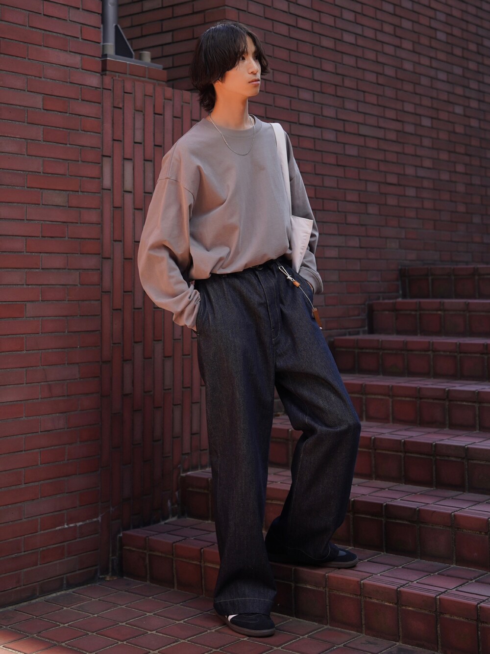 グレー系のTシャツ/カットソー、ブルー系のデニムパンツ、ブラック系のスニーカーを着用したメンズの夏コーディネートの5枚目の写真