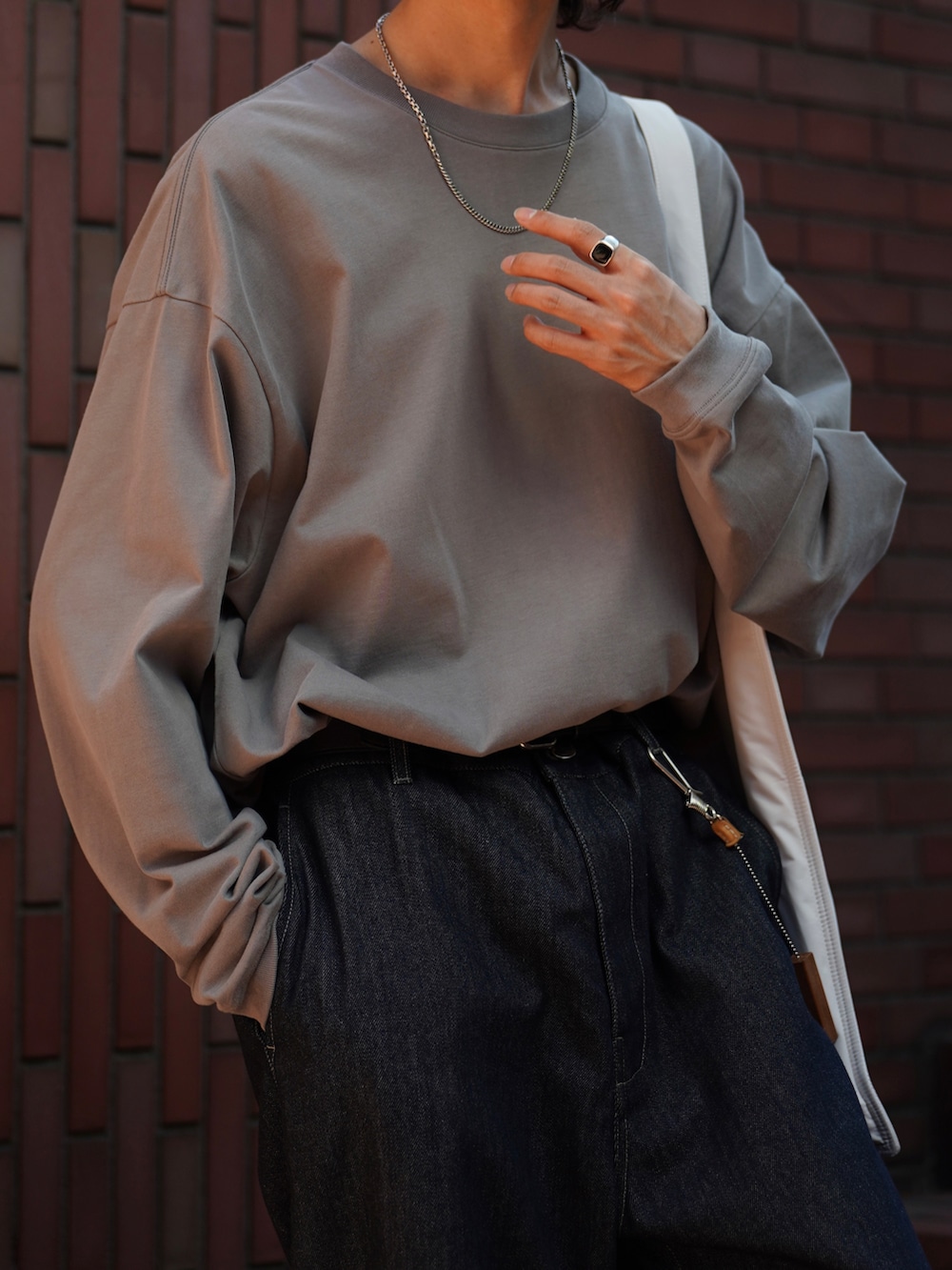 グレー系のTシャツ/カットソー、ブルー系のデニムパンツ、ブラック系のスニーカーを着用したメンズの夏コーディネートの3枚目の写真