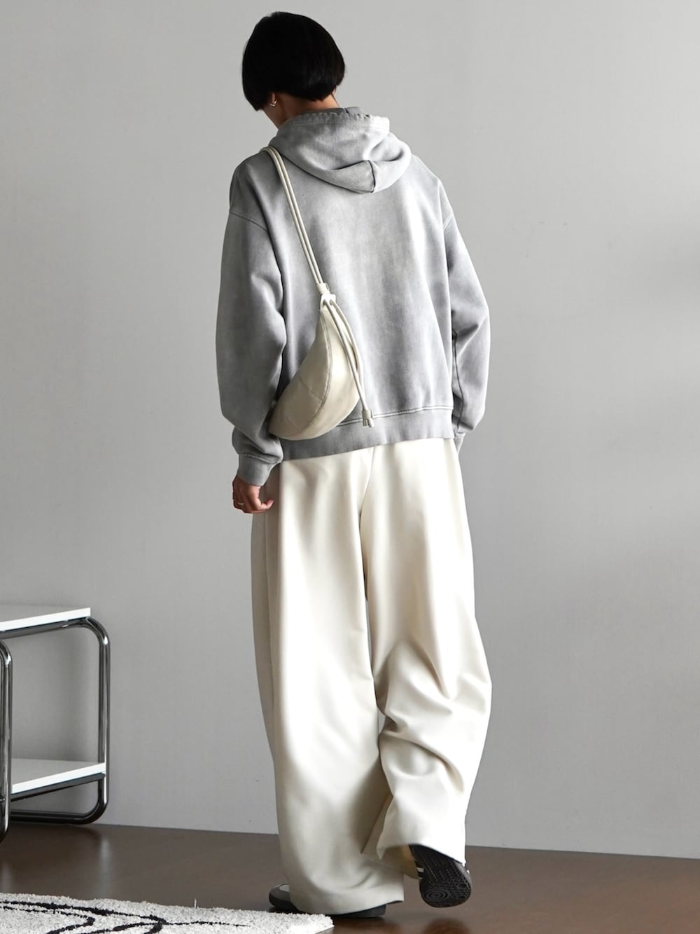 グレー系のパーカー、ホワイト系のスラックス、グレー系のショルダーバッグを着用したメンズの秋コーディネートの2枚目の写真