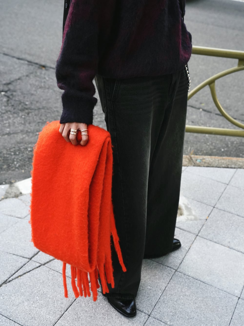 レッド系のニット/セーター、ブラック系のデニムパンツ、ブラック系のブーツを着用したメンズの冬コーディネートの5枚目の写真