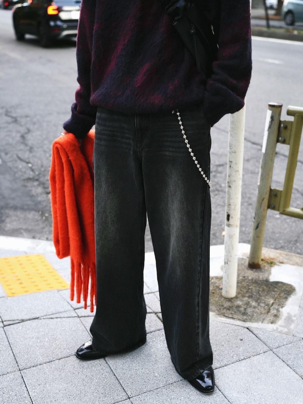 レッド系のニット/セーター、ブラック系のデニムパンツ、ブラック系のブーツを着用したメンズの冬コーディネートの4枚目の写真