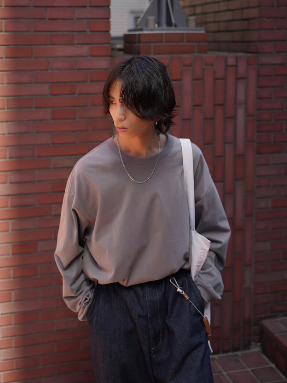 グレー系のTシャツ/カットソー、ブルー系のデニムパンツ、ブラック系のスニーカーを着用したメンズの夏コーディネートの2枚目の写真