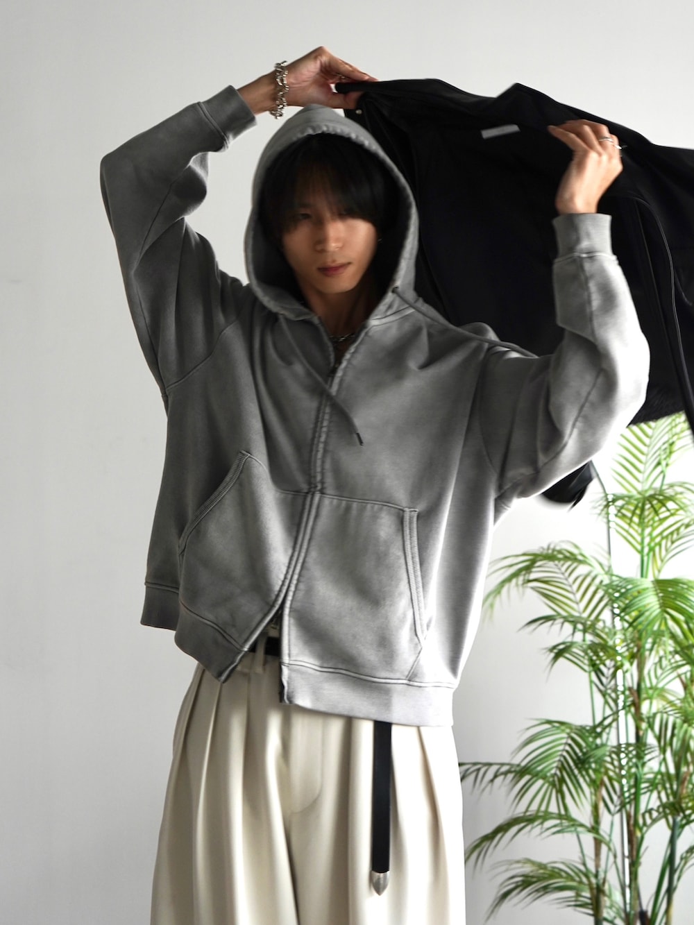 グレー系のパーカー、ブラック系のブルゾン、ホワイト系のスラックスを着用したメンズの秋コーディネートの2枚目の写真